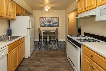 A kitchen with wooden cabinets and a white stove top oven.